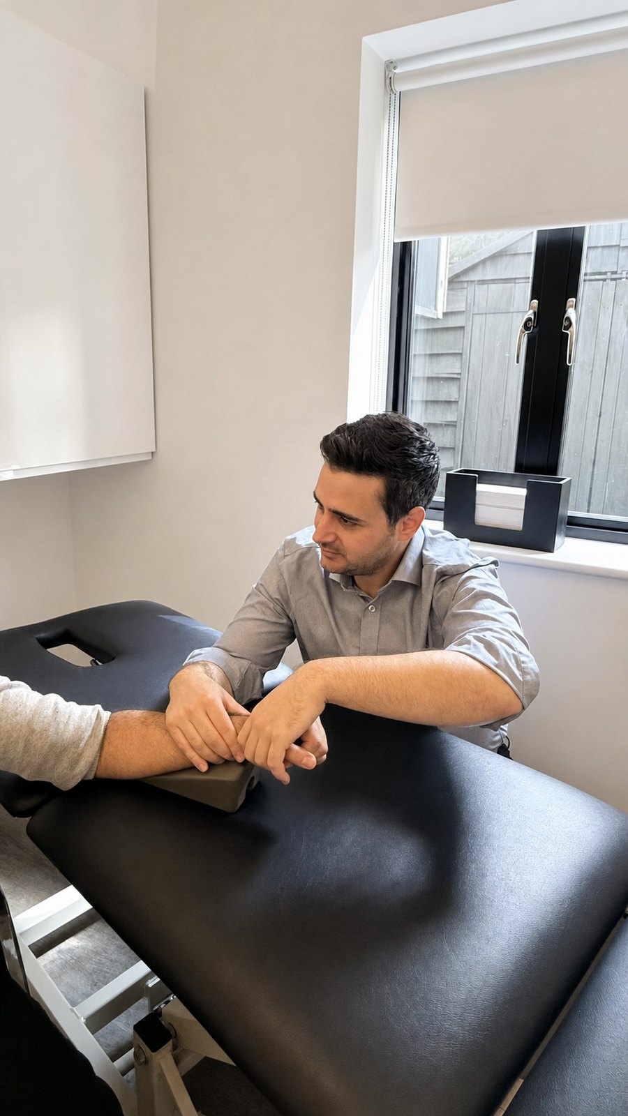 Physiotherapist assessing a patient's arm during post-operative rehabilitation